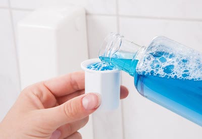 Blue liquid being poured into white plastic cap