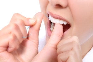 A person using string floss in between teeth